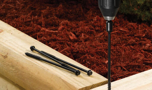 This image depicts a FastenMaster TimberLOK screw being screwed into a piece of wood.